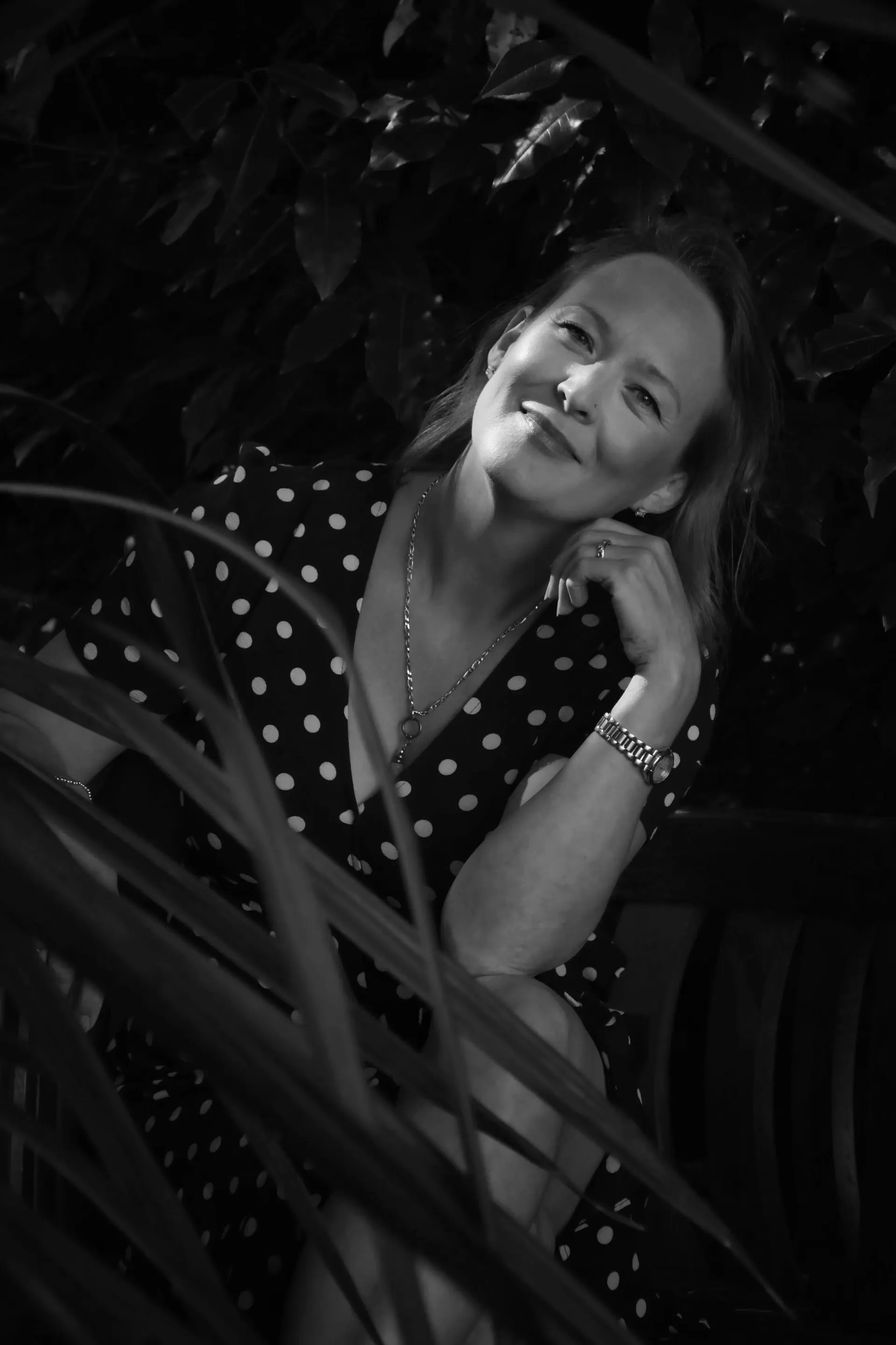 Shelley Doyle, founder of The Communiverse, seated in a garden with dappled light